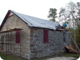 With the stonework complete - it was time to relieve the schoolhouse of it's rotted roof.  Kevin Lord, went at it full force with a crow bar, while Heather and her father scurried to pick up the falling debris.